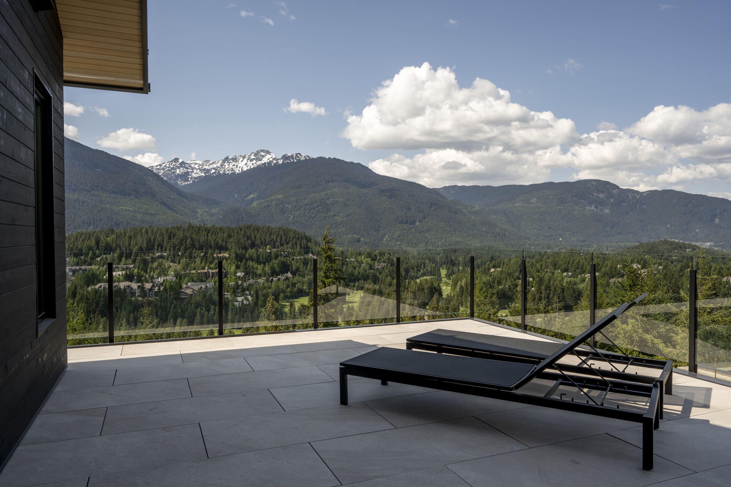 Aluminum glass railing on a BC mountain property with non-combustible posts and tempered glass panels overlooking forested valley